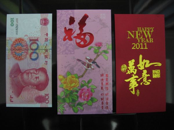 kaksi punaista kirjekuorta ja 100 Yuanin seteli.